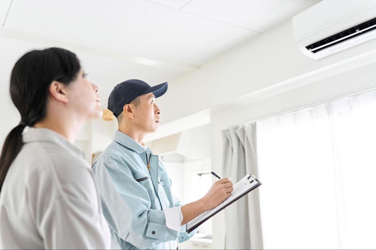 Expert noteert samen met een huurder de staat van de airco tijdens een plaatsbeschrijving.